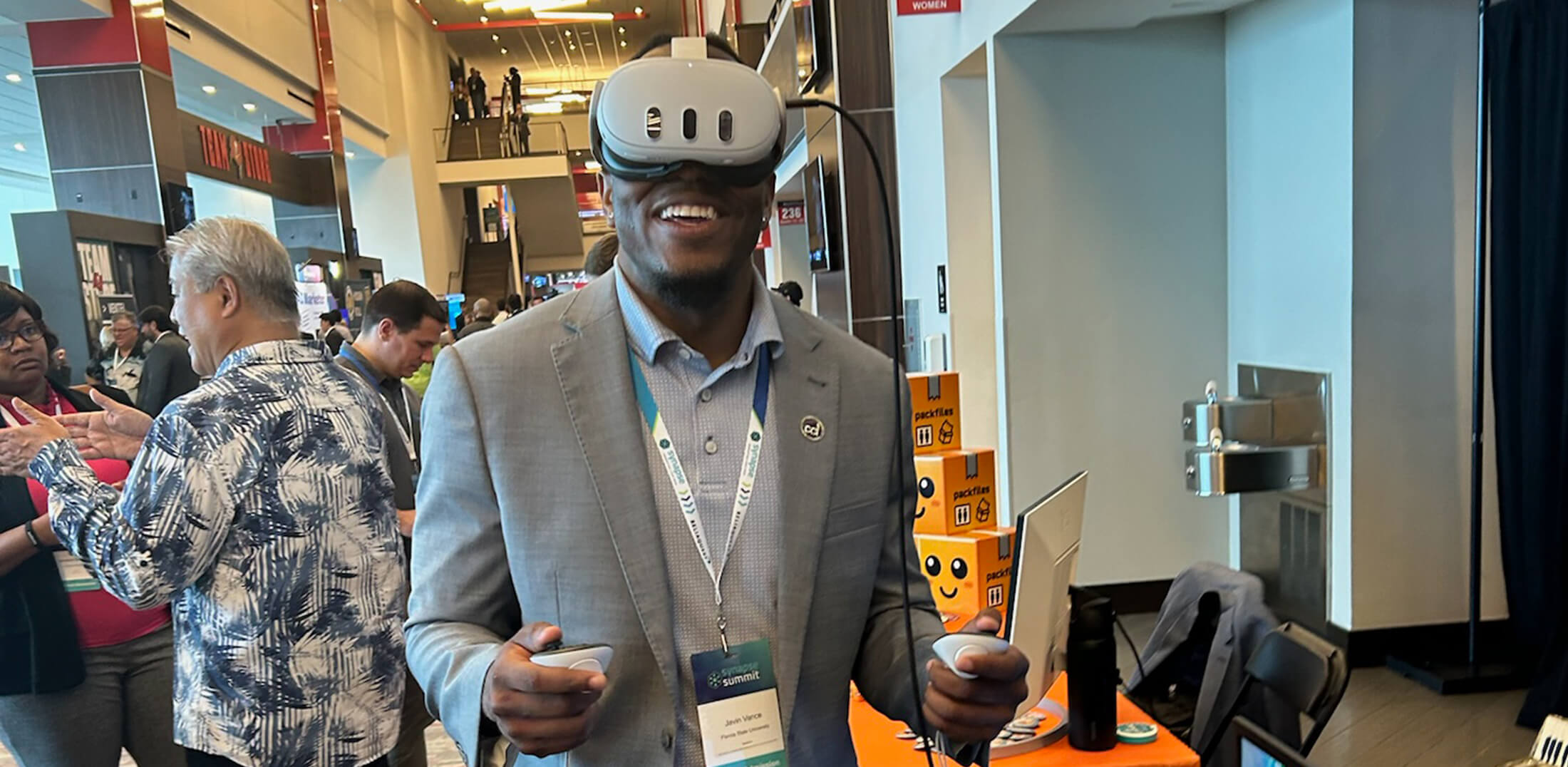 a smiling man doing a VR demo at a trade show or convention